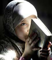 دختر بچه اي در حال بوسيدن قرآن