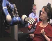cathy uses the mind-controlled robotic arm to picked up a bottle of coffee and sipped from it. 