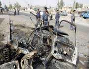 iraqi policemen stand at the scene of a car bomb attack