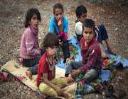 syrian children sit on the ground at a camp