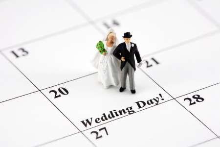 Miniature bride and groom on a calendar that says Wedding Day
