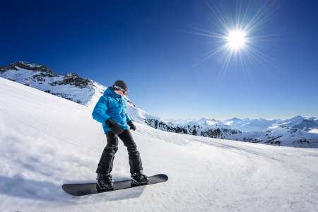 Snowboarder on piste in high mountains