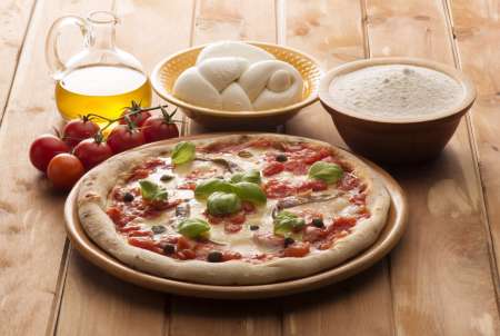 pizza with ingredients on wooden table