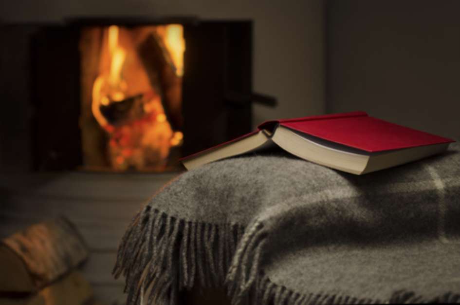 Peaceful and warm image of a open book by fireplace.
