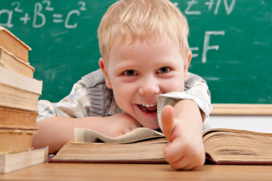Cheerful smiling  little boy sitting at the table.