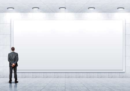 Business person standing near a blank billboard