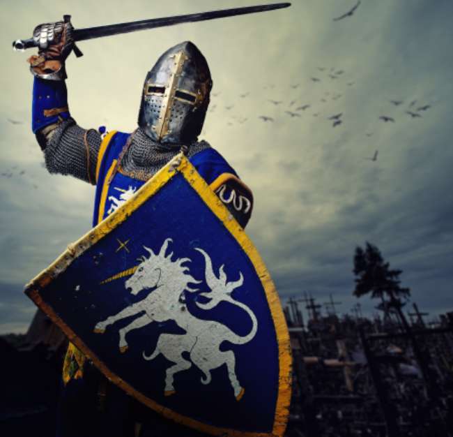 Medieval knight against hill full of crosses.