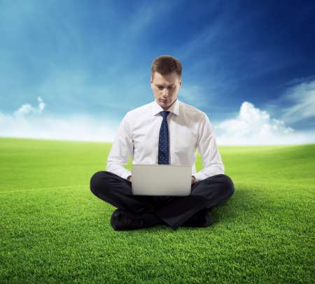 business man with notebook sitting on grass