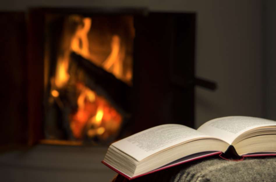 Peaceful and warm image of a open book by fireplace.