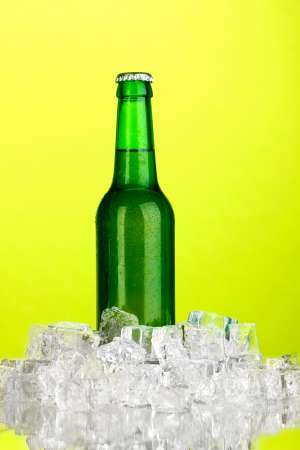 Beer bottle in ice on green background