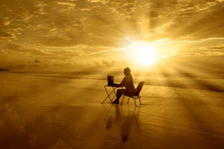 Girl-with-laptop-at-sunset-on-the-beach
