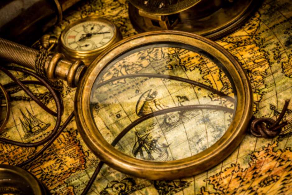 Vintage magnifying glass lies on an ancient world map