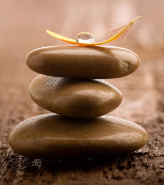 Pile of brown massage stones on wooden background