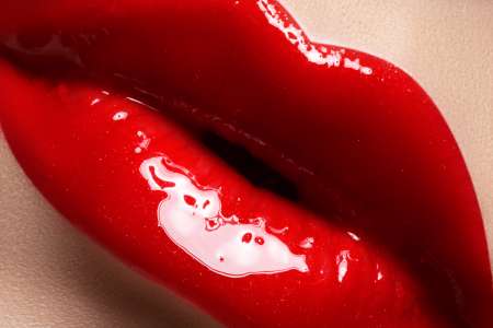 Close-up of lips with bright fashion red glossy makeup