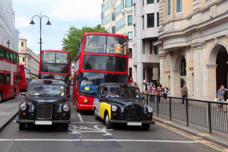 Red double-deckers with tourists and taxi on street of London