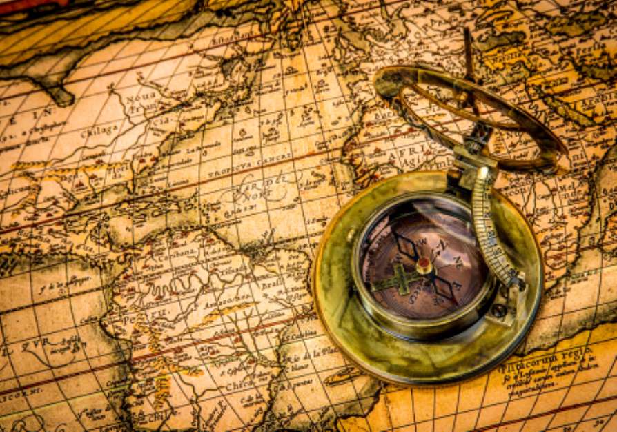 Vintage compass lies on an ancient world map.