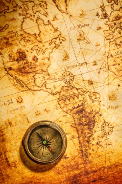 Vintage compass lies on an ancient world map.