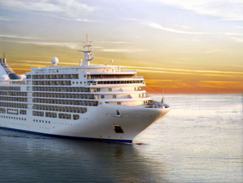 Luxury cruise ship sailing from port on sunset