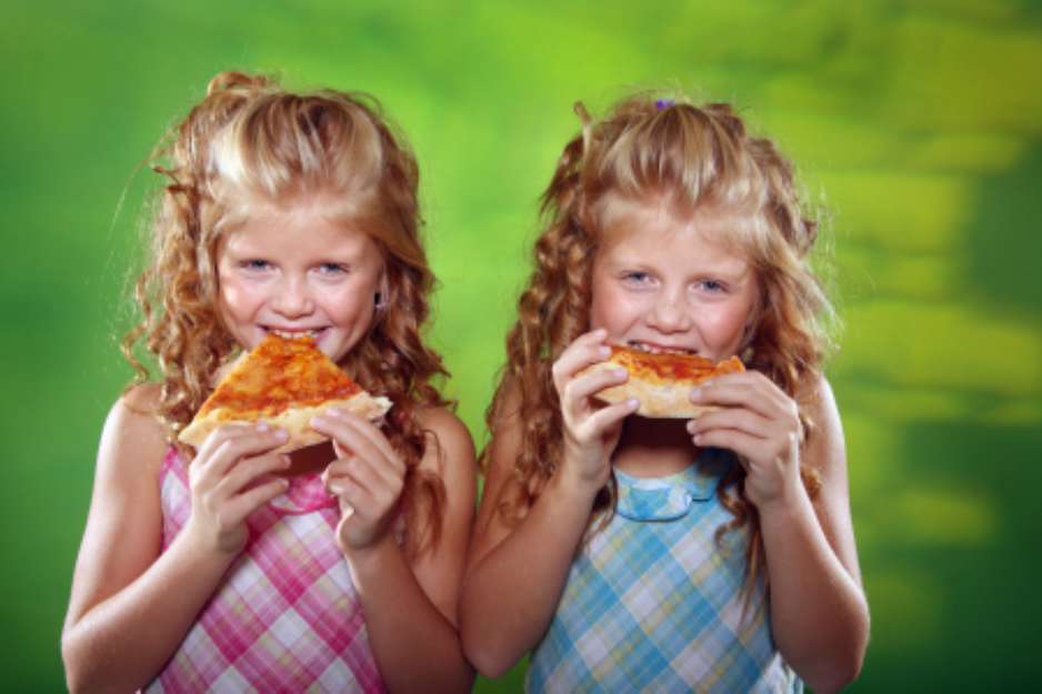 Two girls eating pizza on the green background