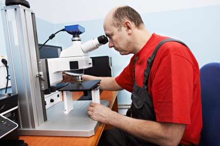 worker checking probe with industrial microscope