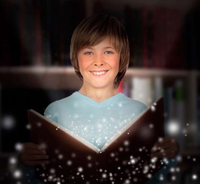 Preteen boy with a lighted book reading