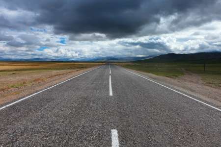 An empty desert road with dark and foreboding storm clouds