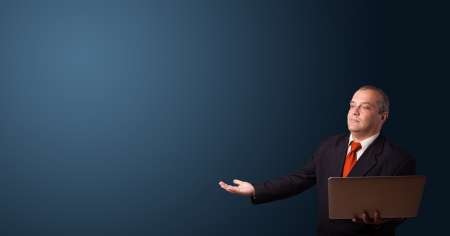 businessman holding a laptop and presenting copy space