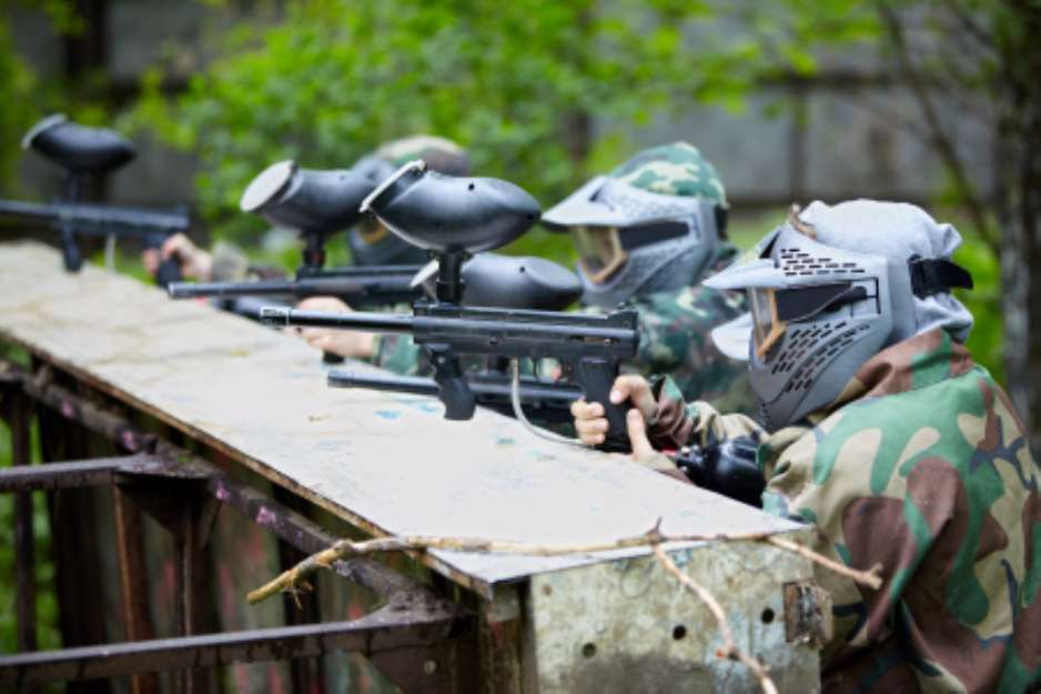 Four paintball players in camouflage and protective masks aims