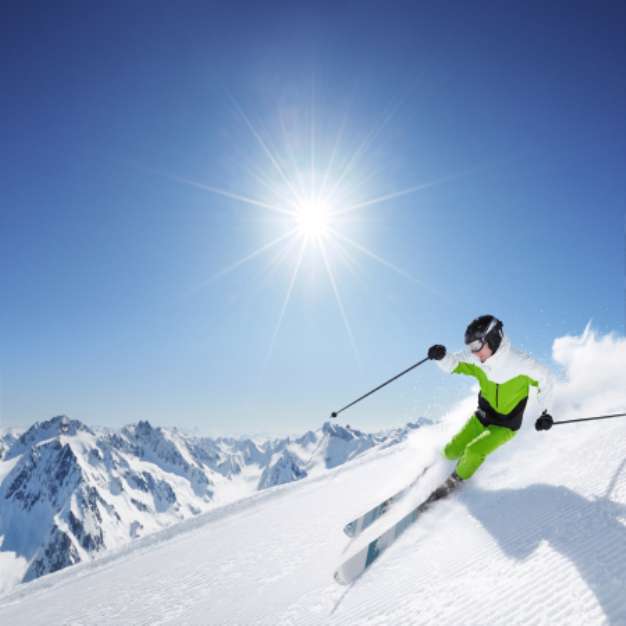 Skier in mountains, prepared piste and sunny day