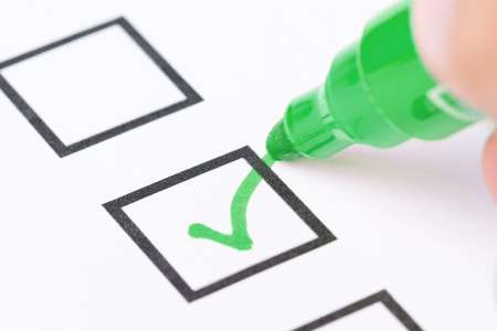Macro shot of human hand drawing green check mark in checklist b