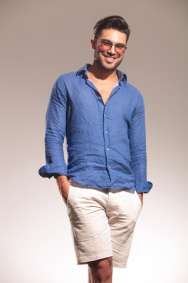 Picture of a handsome young fashion man smiling to the camera with both hands in his pocket.