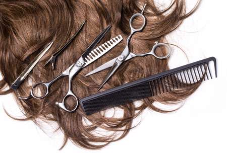 Long brown hair with scissors on close up isolated on white background