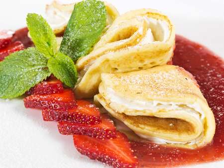 A set of pancakes with strawberries and sauce on white plate on white background isolated