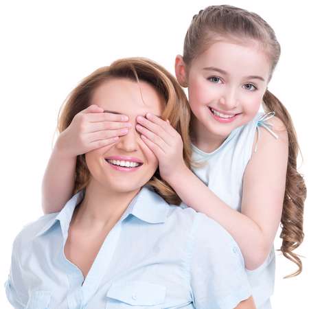 Young daughter closes hands eyes mom - isolated. Happy family people concept.
