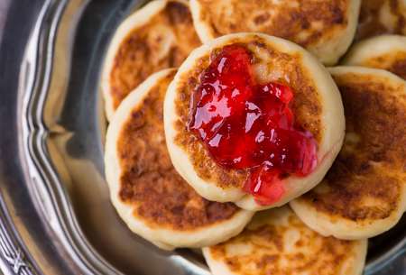 Cottage cheese pancakes with currant jam, closeup, top view