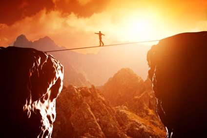 Man walking and balancing on rope over precipice in mountains at sunset. Concept of business, risk taking, challenge, concentration.